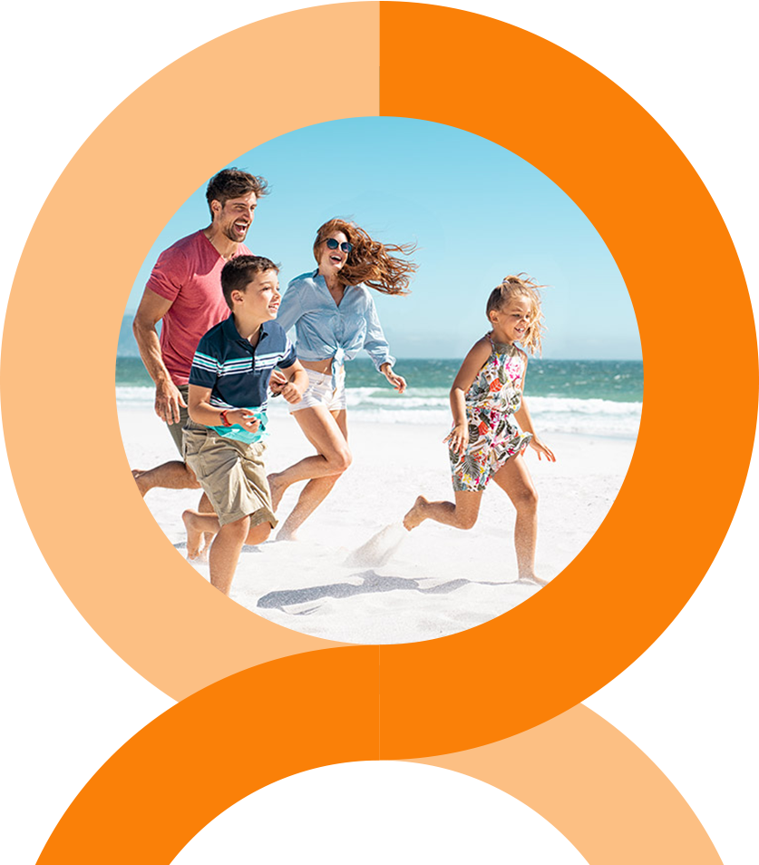 Rings-home-family A man and woman stand closely together, smiling at the camera. The woman wears a pink floral dress, and the man wears a pink striped shirt and glasses. They are outdoors with greenery in the background.