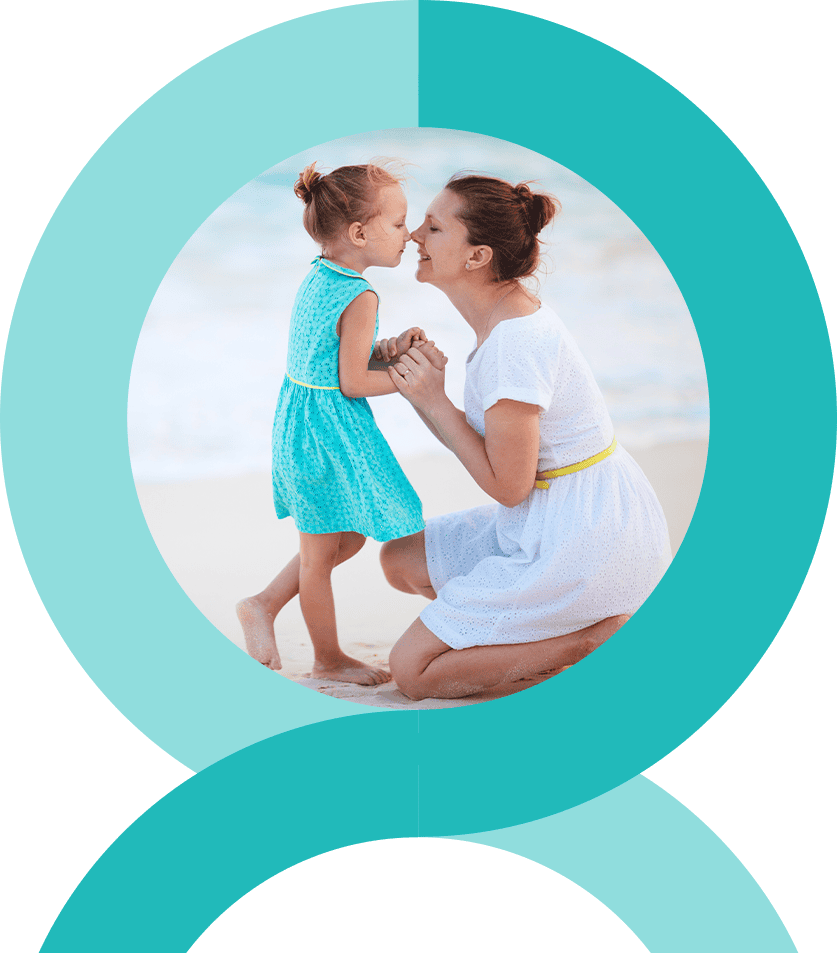 Rings-home-main A woman kneels, smiling at a child in a blue dress, both playfully interacting on a beach. Circular design frames the scene.